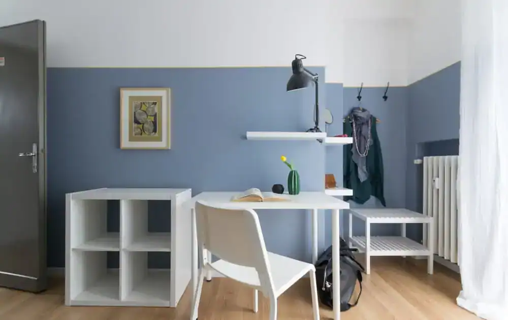 scrivania bianca con lampada vicino a parete blu