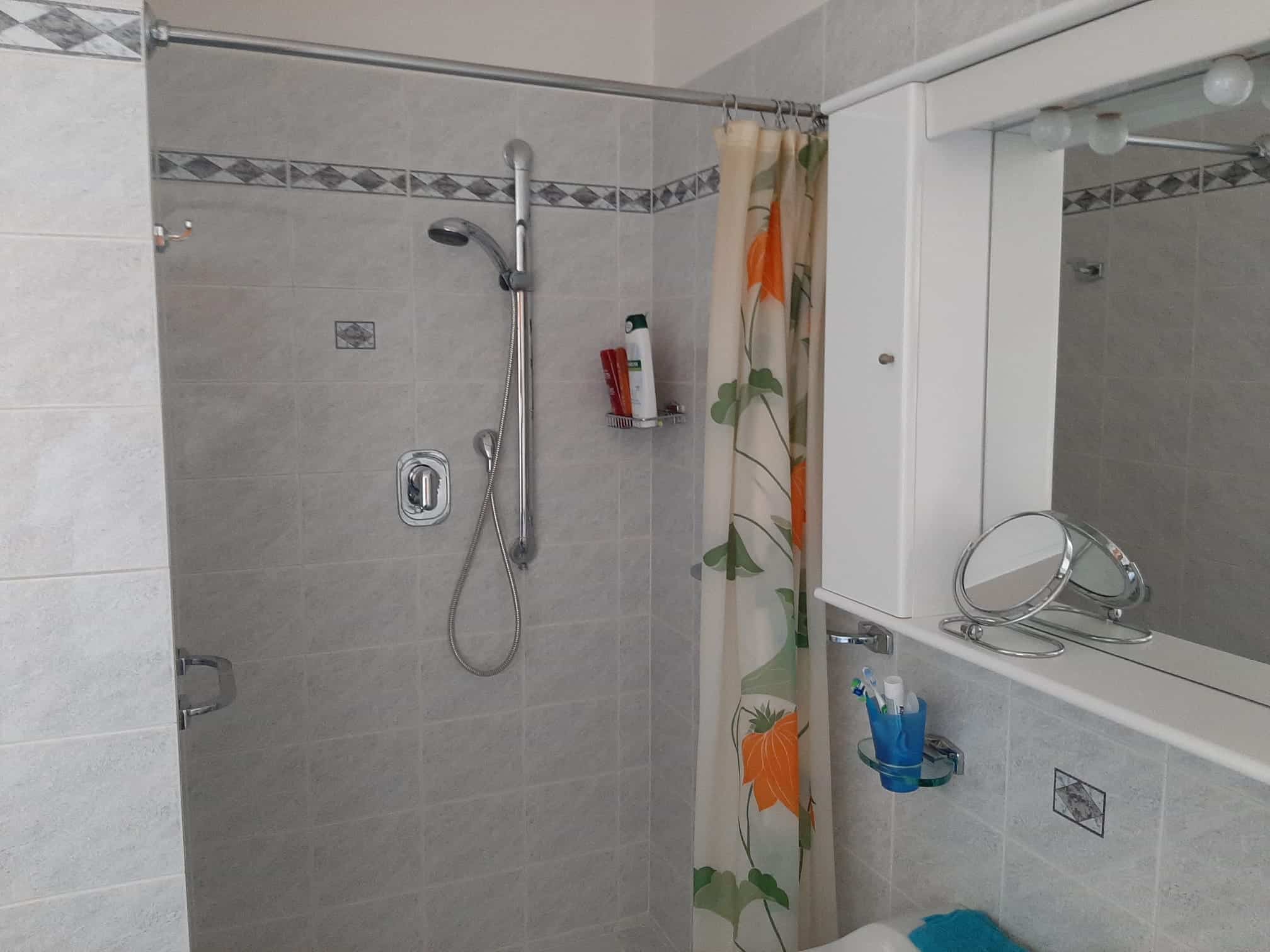 doccia con parete in piastrelle e specchio