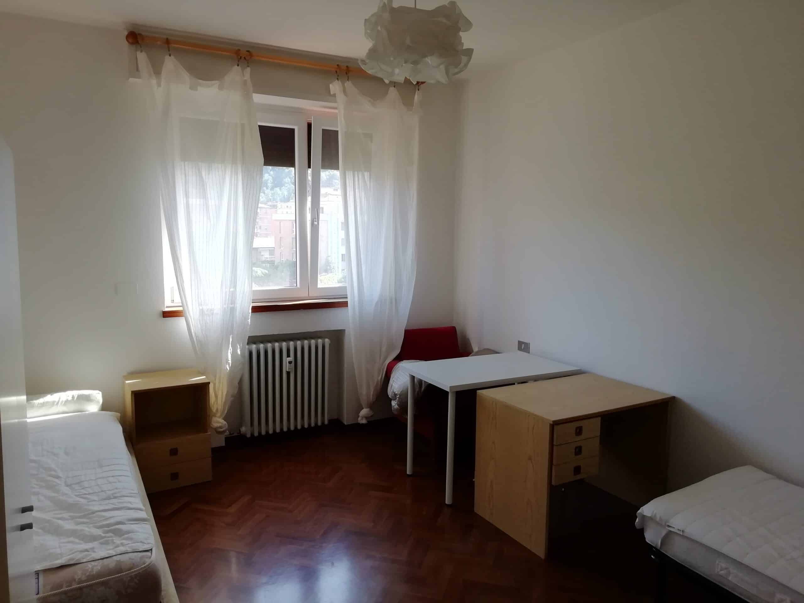 camera con letti e scrivanie vicino a una finestra