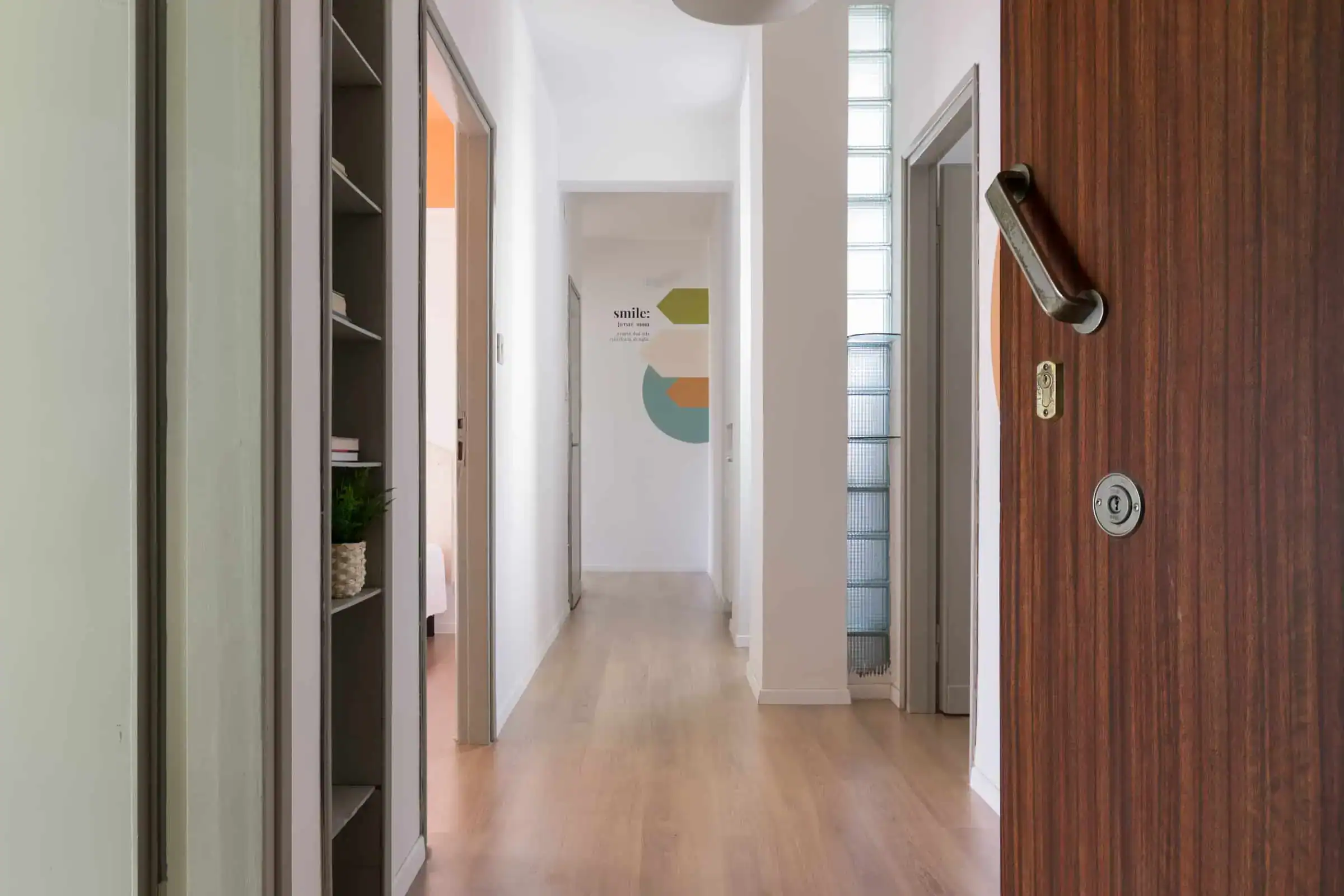 corridoio luminoso con porta di legno e pareti bianche