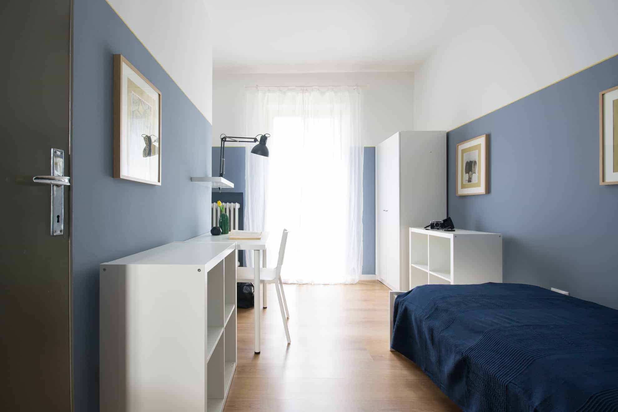 camera con pareti blu e letto vicino alla finestra